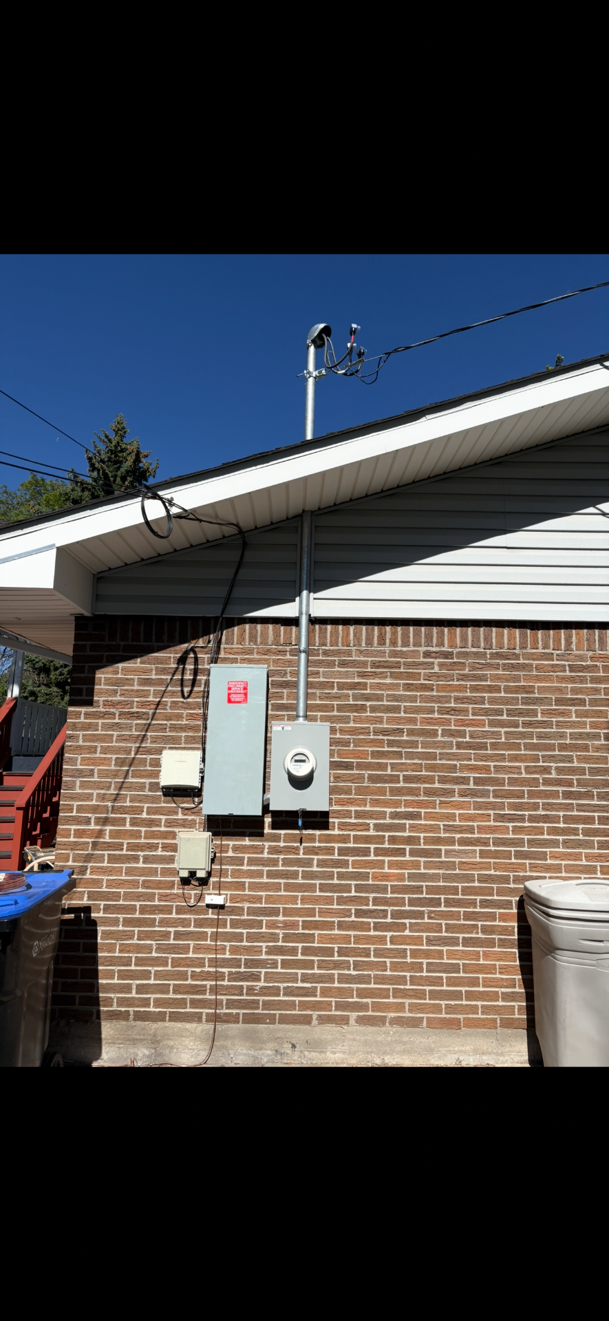 New service mast, meter and emergency disconnect installed on a brick wall