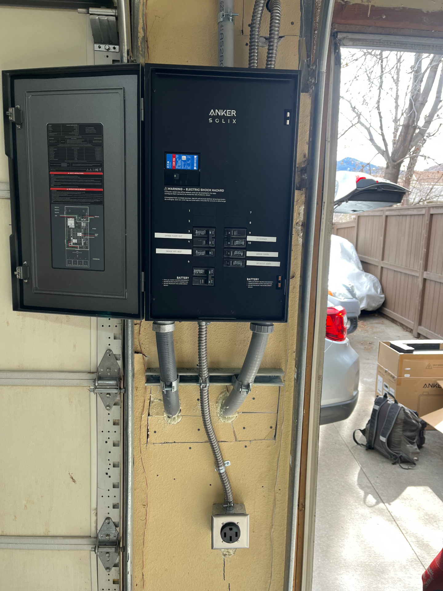 Anker SOLIX smart load center mounted in a garage with labeled EV charger and battery circuits
